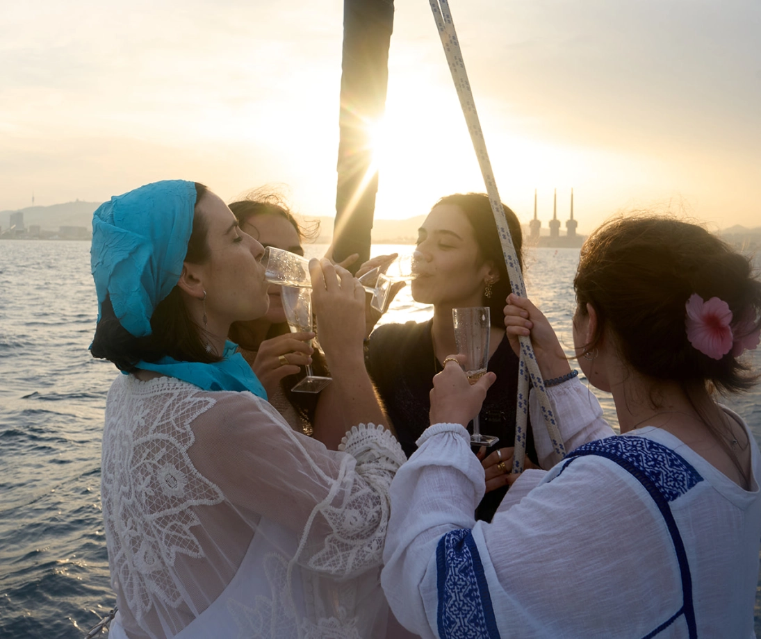 Gruppo di persone che si godono un’uscita in barca a vela di lusso navigando vicino alla città al tramonto