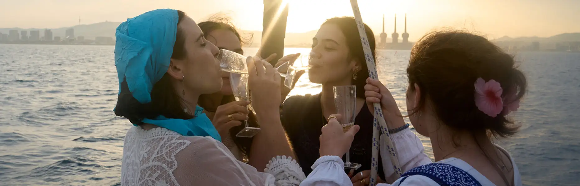 Group of friends toasting with cava at sunset on a boat off the coast of Barcelona