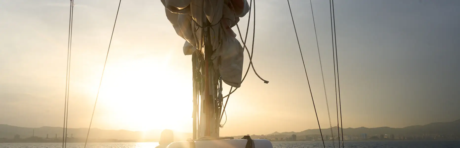 Sonnenuntergang auf dem Boot vor der Küste von Barcelona, mit der untergehenden Sonne über dem Meer und den Bergen im Hintergrund