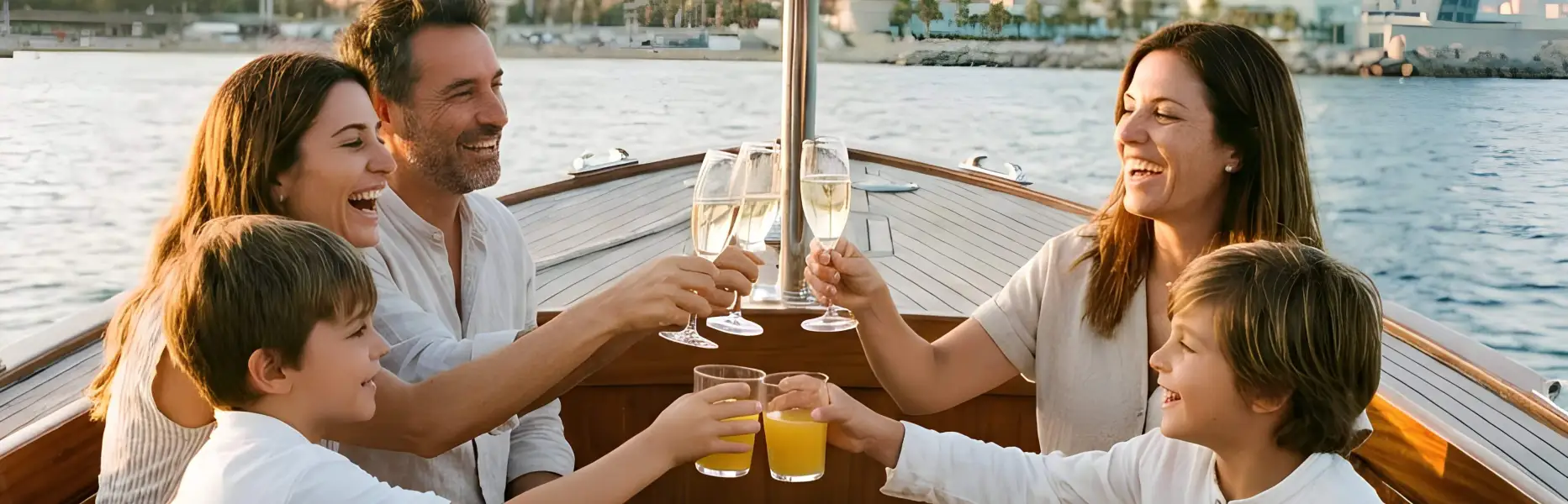 Family with children making a toast on a boat at sunset with the city of Barcelona in the background