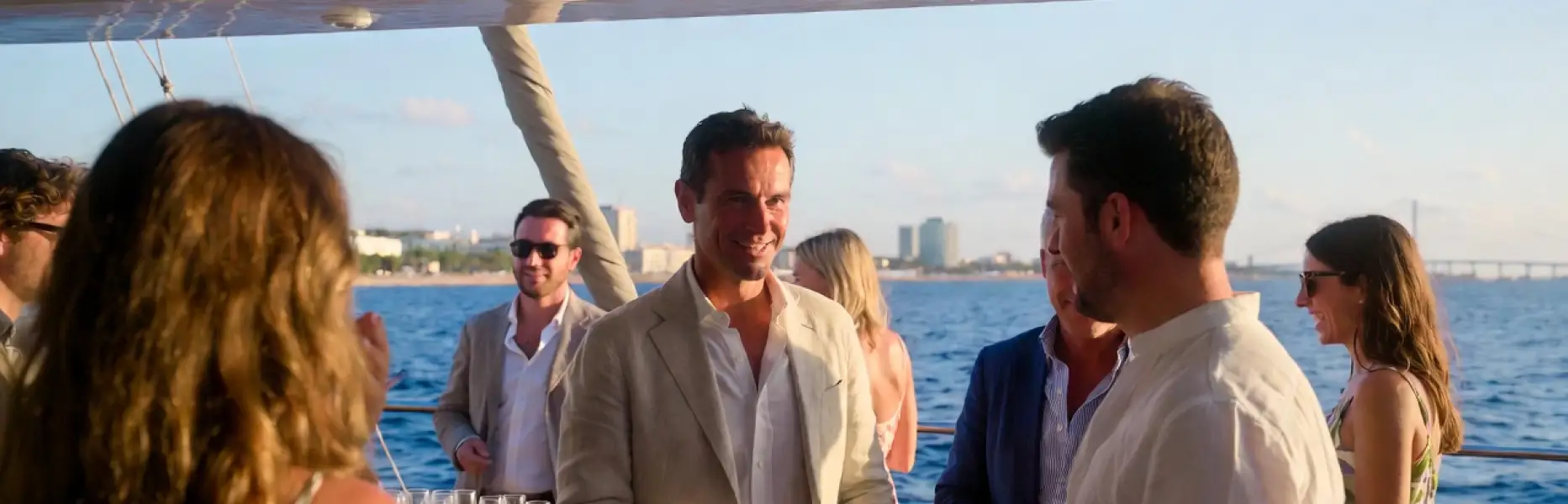 Gruppe von Menschen, die bei Sonnenuntergang vor dem Meer eine luxuriöse Charter-Yacht-Veranstaltung genießt