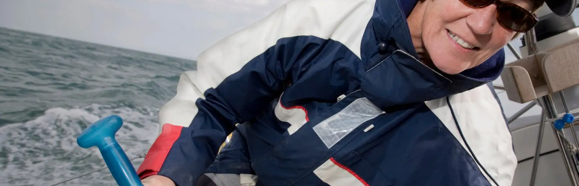 Smiling woman sailing a yacht on the open sea during a charter