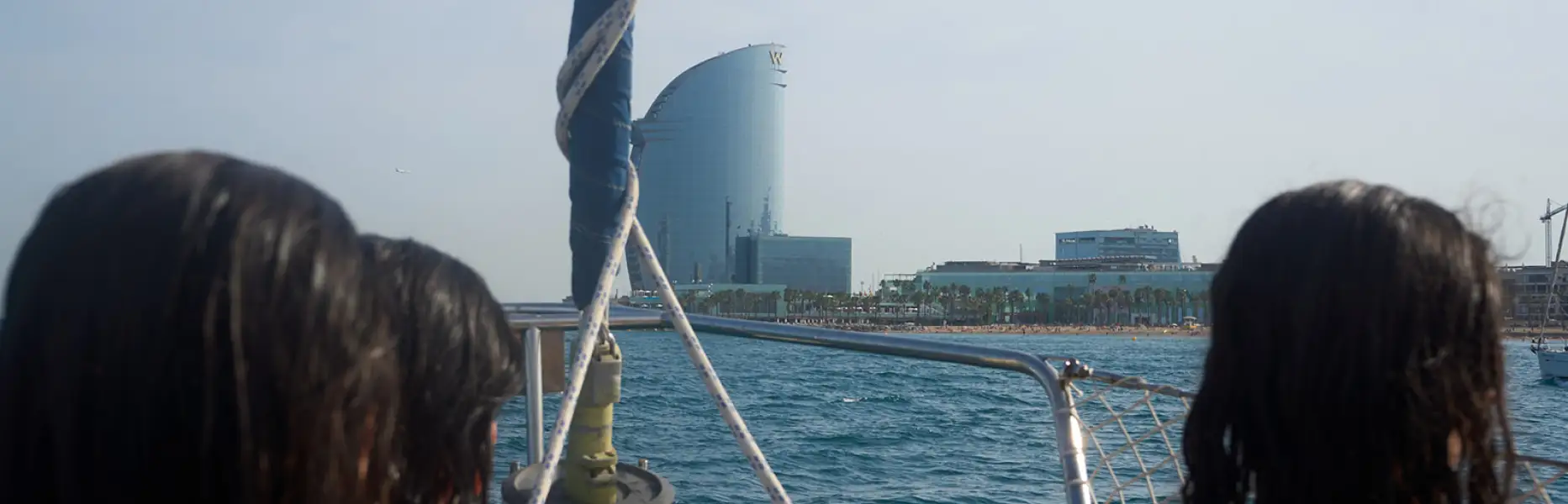 Dos chicas en un charter en velero navegando frente al hotel W Barcelona en un día soleado