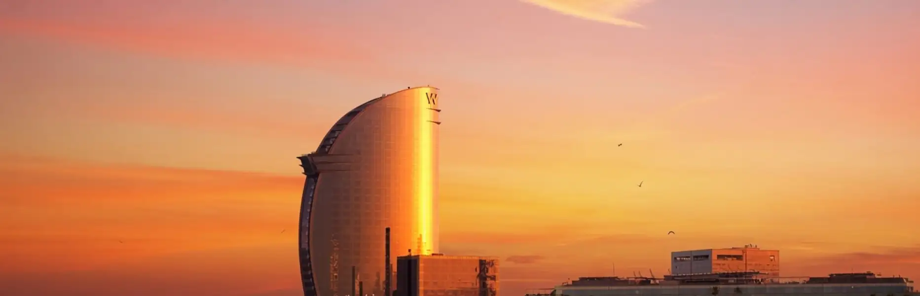 Alba dorata sull'hotel vela di Barcellona vista dal mare su una barca a vela privata