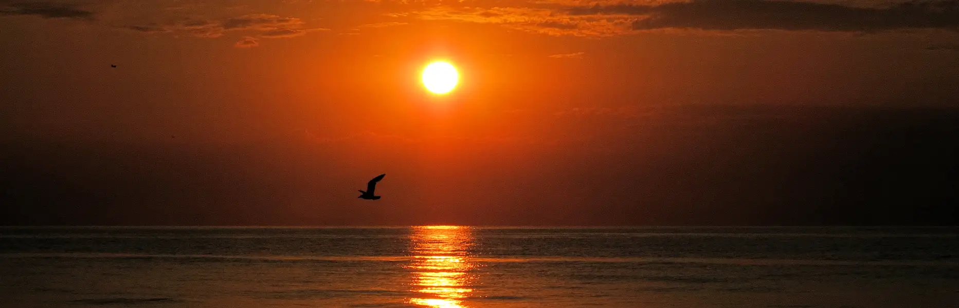 Soleil se levant sur la mer calme avec un voilier à l’aube face à Barcelone