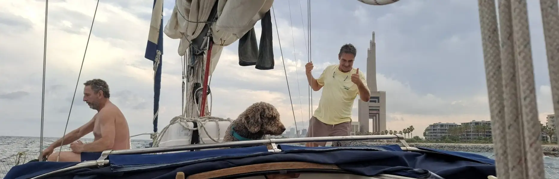 Grupo disfrutando en la cubierta de un velero privado navegando frente a la costa de Barcelona