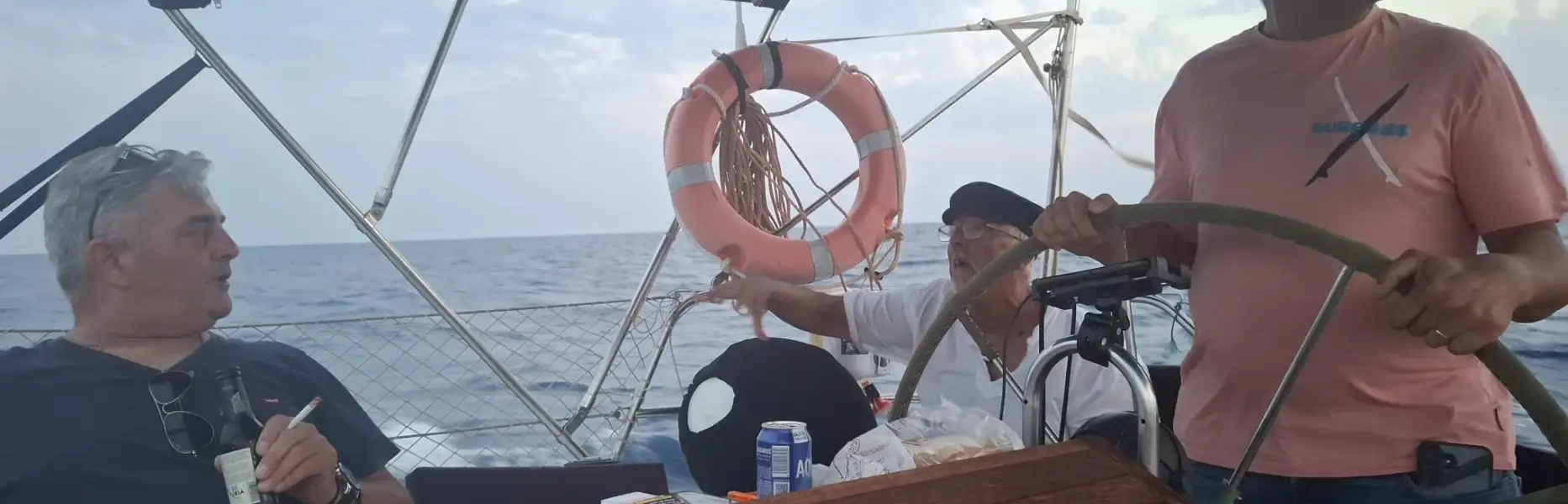 Freundesgruppe auf einem privaten Segelboot mit Profi-Skipper beim Sonnenuntergang im Mittelmeer