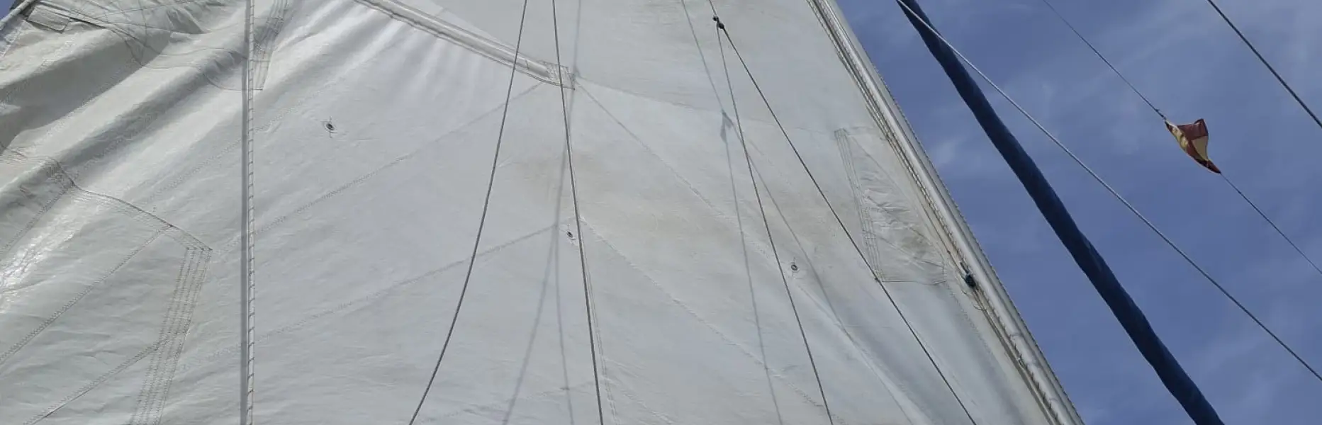Grand-voile d’un voilier naviguant sous un ciel bleu en Méditerranée