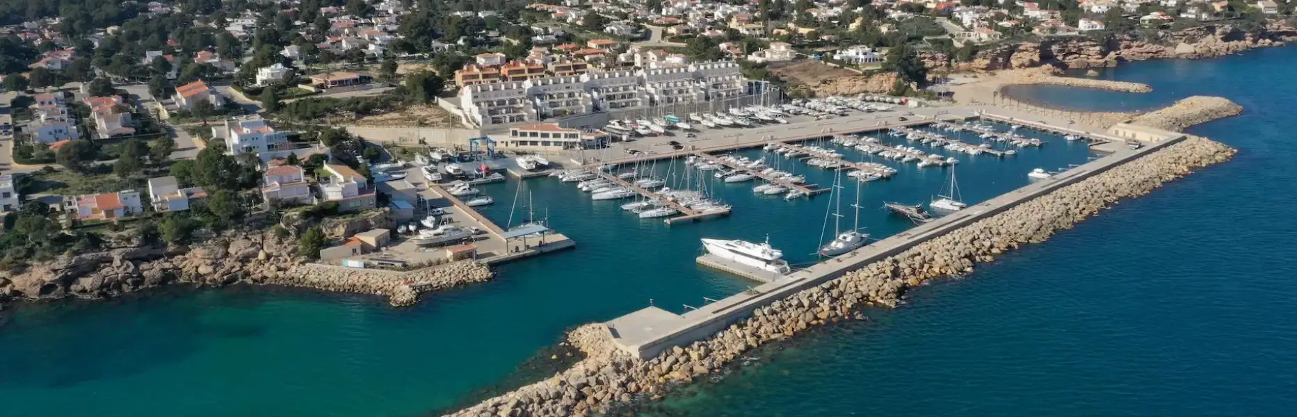 Vue aérienne d’un port de plaisance avec des voiliers amarrés le long de la côte et des montagnes en arrière-plan près du delta de l’Èbre