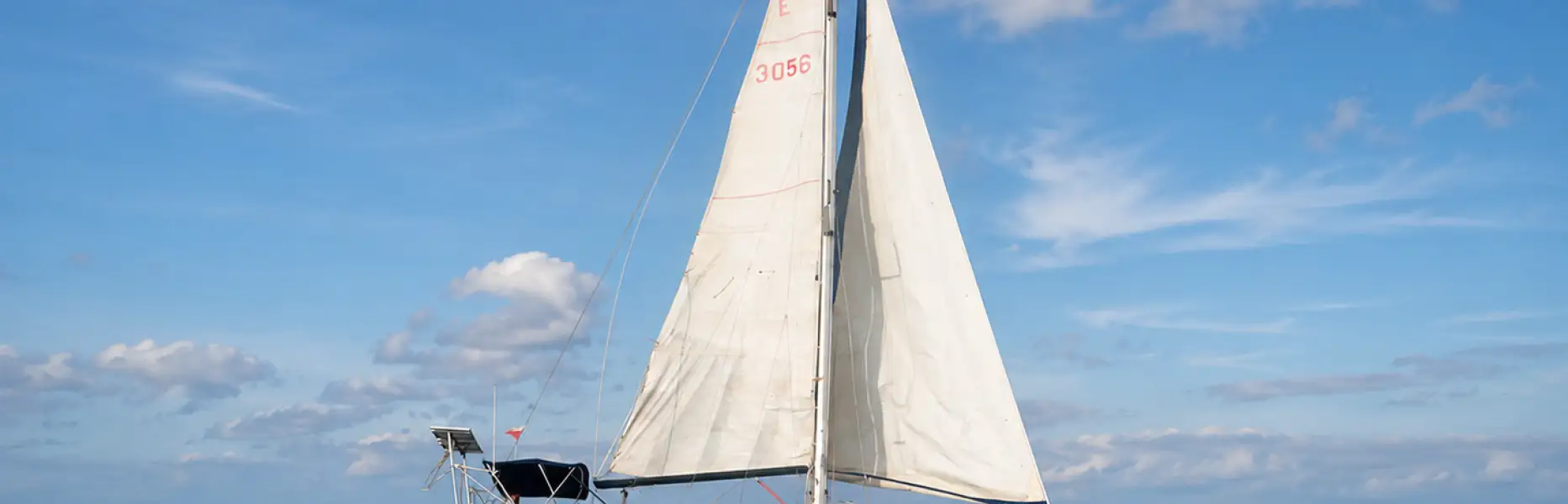 Cruising yacht sailing under sail on the open sea beneath a blue sky with scattered clouds