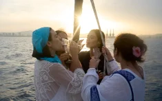 Groupe d’amies trinquant au cava au coucher du soleil sur un bateau au large de la côte de Barcelone