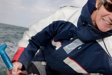 Frau steuert ein Segelboot im Charter