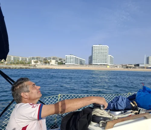 Patrón navegando en velero frente a la costa de Barcelona en un día soleado